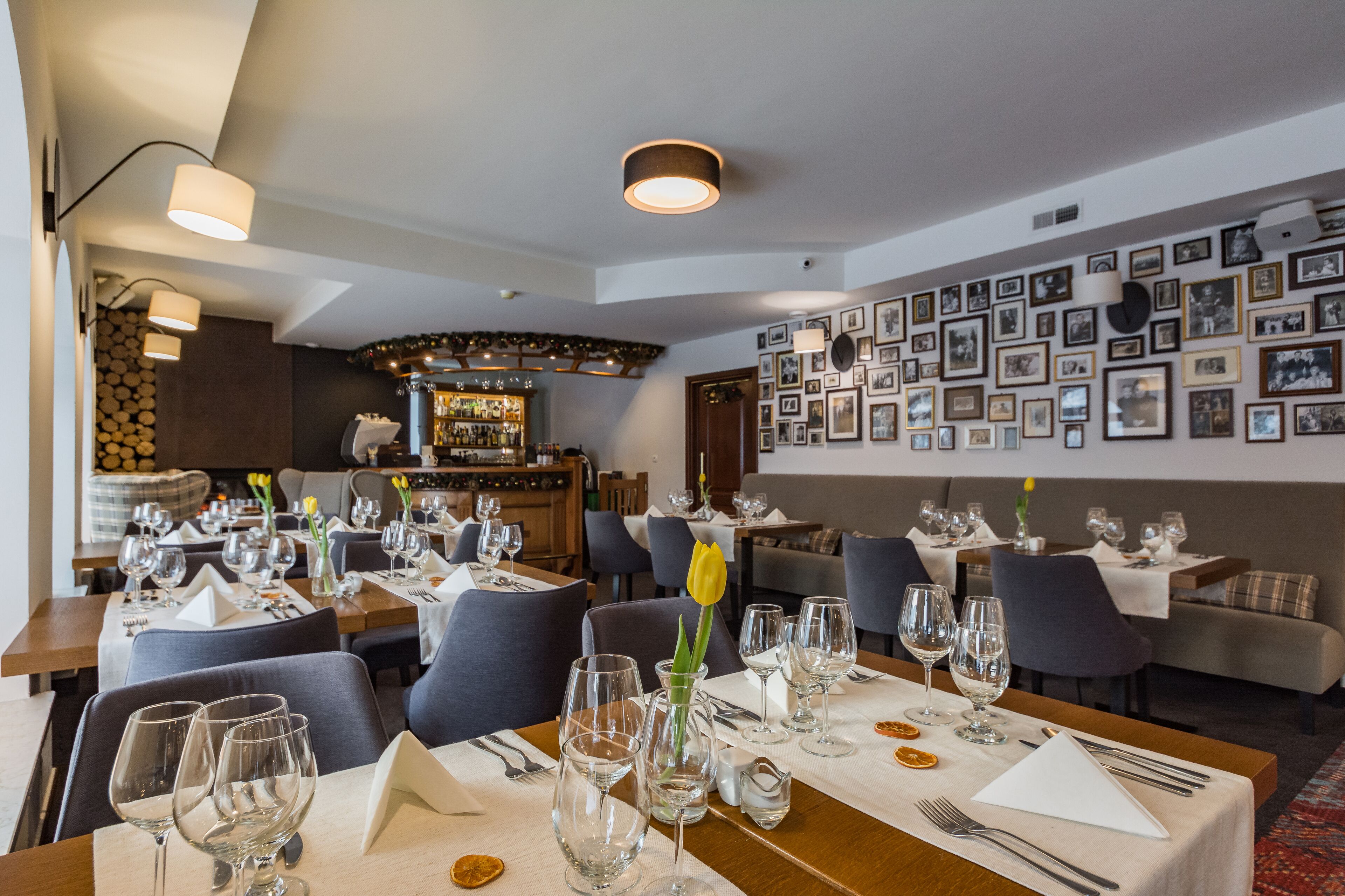 Un ristorante con diversi tavoli apparecchiati per consumare un pasto, con un'area bar sullo sfondo.