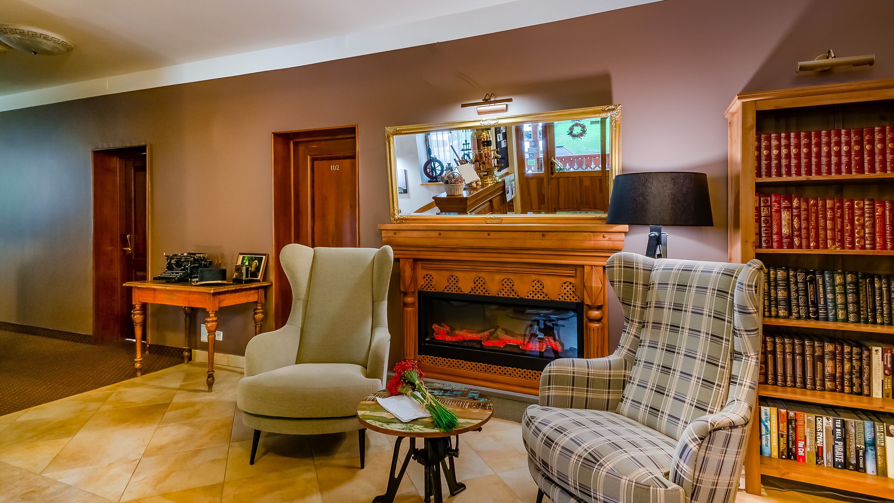 Una sala de estar acogedora con chimenea, una estantería llena de libros y un rincón de descanso confortable.