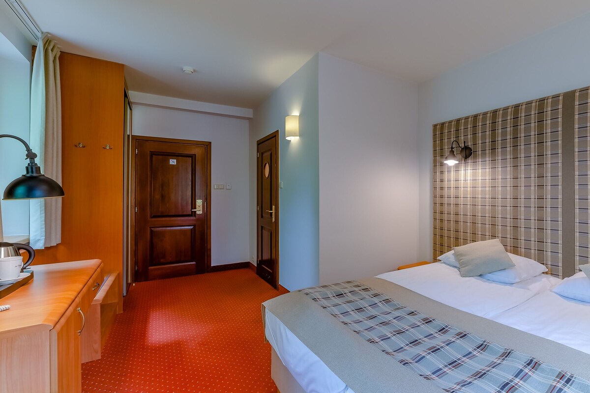 Habitaci ón de hotel con cama, escritorio, lámpara y pared con estampado de cuadros.