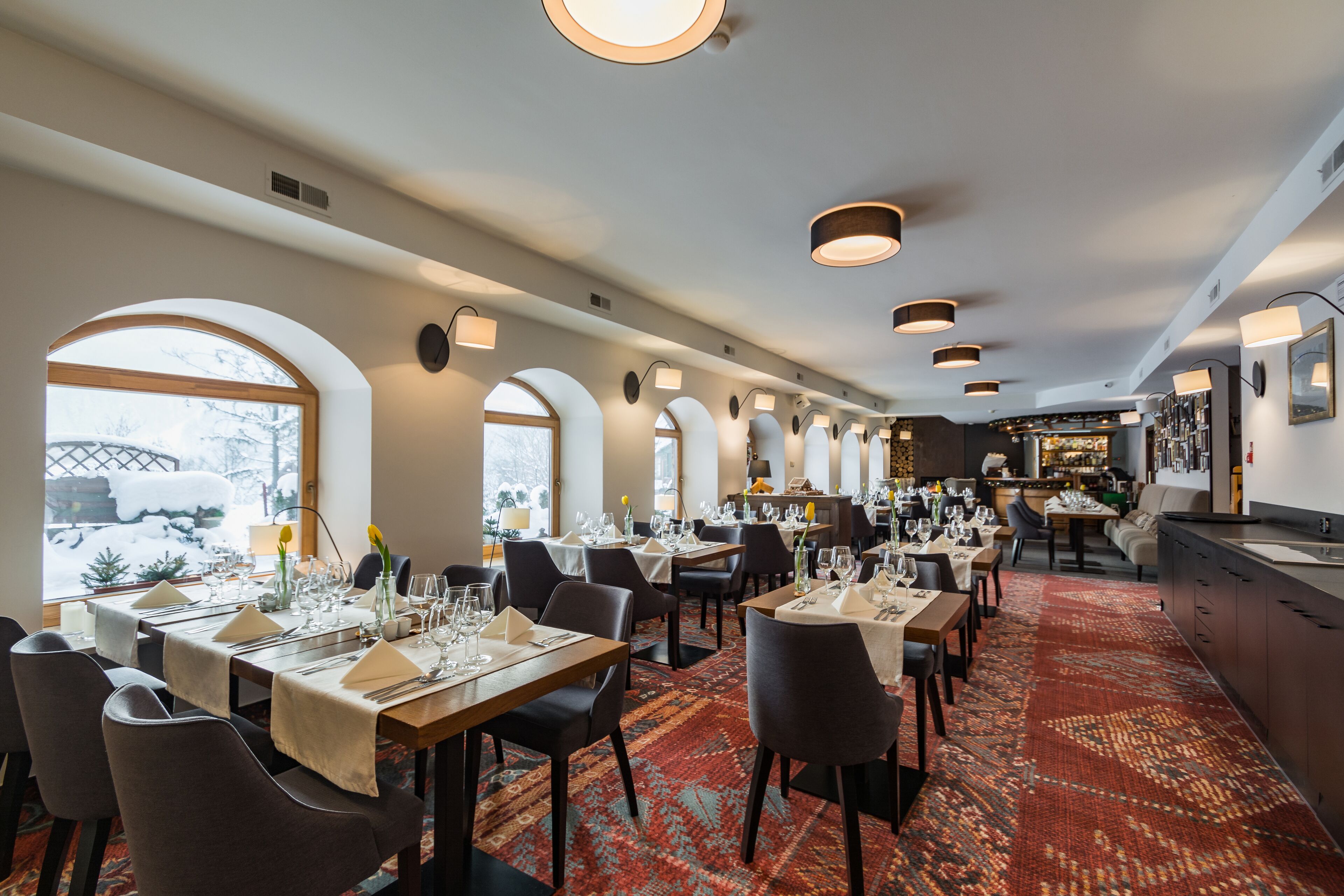 A restaurant with multiple dining tables, chairs, and a bar area.