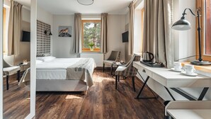 Habitación de hotel moderna con una cama grande, un escritorio con cafetera, una silla y vistas al exterior.