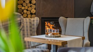 Un rincón acogedor con una chimenea, cojines de cuadros y una mesa con vasos de whisky.
