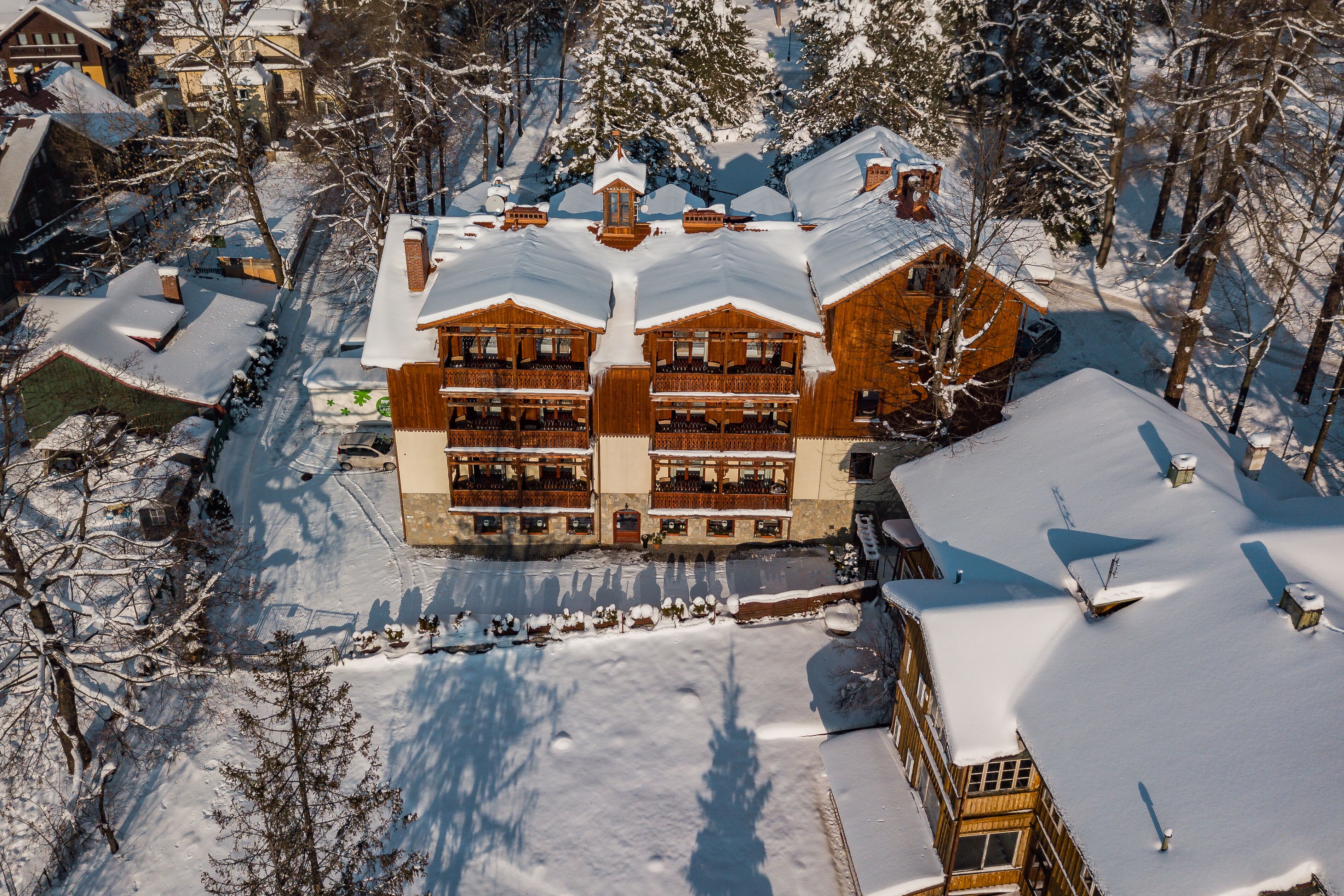 Un edificio de madera grande y de varios pisos con balcones, rodeado de árboles cubiertos de nieve y un cielo despejado.
