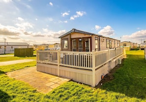 A mobile home with a fenced deck and a covered outdoor area.