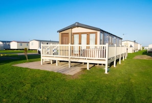A mobile home with a porch and a fenced deck, surrounded by other similar homes.