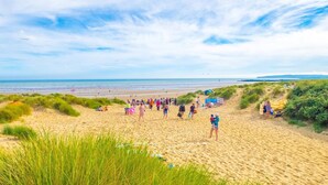 Une plage avec des gens, des dunes et la mer.