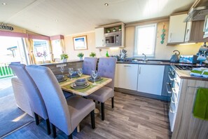 A modern kitchen with a dining area, featuring a table set for two, a microwave, and a stove.