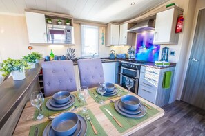 Une cuisine compacte dotée d’appareils électroménagers modernes, un coin repas avec une table pour quatre personnes et une petite fenêtre laissant entrer la lumière naturelle.