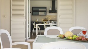 Comedor con una mesa dispuesta para dos personas, sillas y un arreglo de frutas.