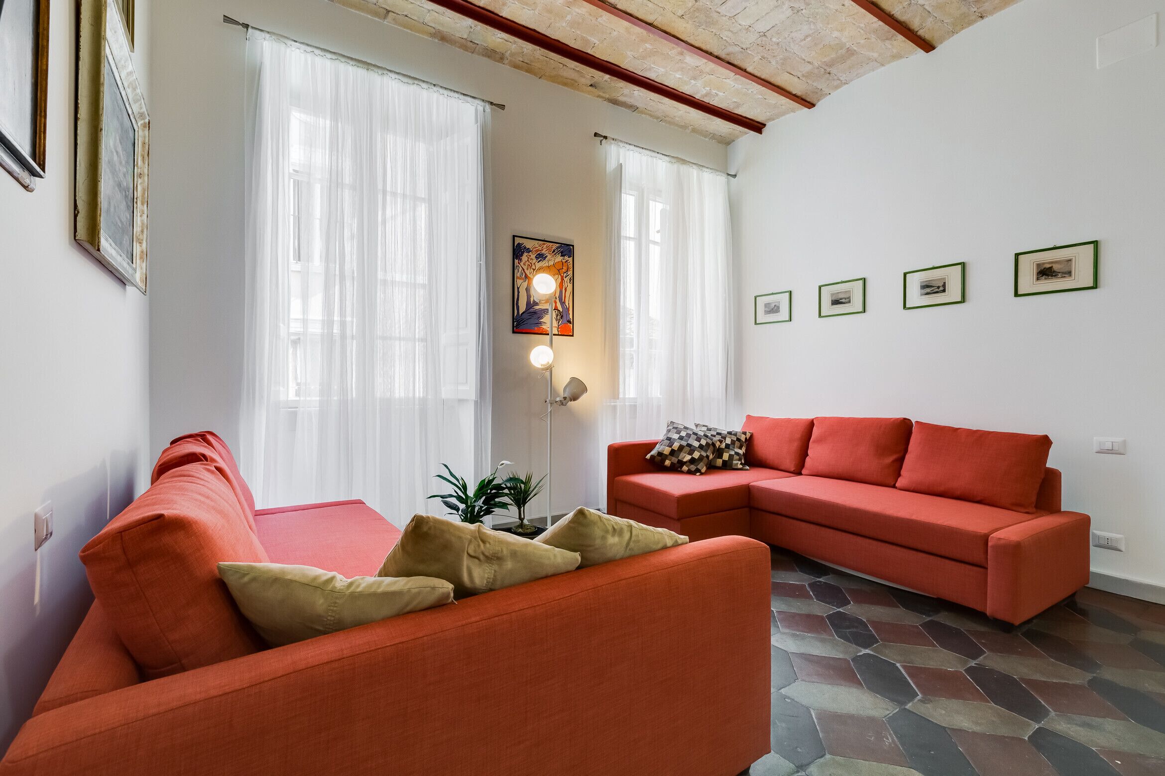 A living room with two red sofas, a floor lamp, and a painting on the wall.