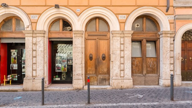 A building with three arched doorways, numbered 107, 108, and 109, with a cobblestone street in front. - Monti Colosseum Apartment (Roma)