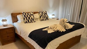 Ein ordentlich bezogenes Bett mit einem schwarz-weiß gemusterten Kopfkissen, einer weißen Decke und einem Handtuch.