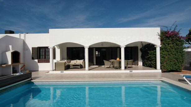 Eine moderne Villa mit Swimmingpool, Sitzbereich im Freien und einer überdachten Terrasse.