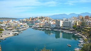 A coastal town with a marina, buildings with balconies, and a clear sky. - Footsteps to the beach! (Agios Nikolaos)