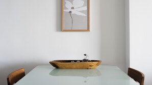 A dining table with a wooden bowl centerpiece, framed artwork on the wall, and two chairs. - Footsteps to the beach! (Agios Nikolaos)