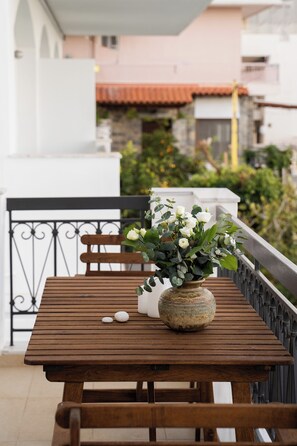Ein Holztisch mit einer Vase voller weißer Blumen auf einem Balkon.
