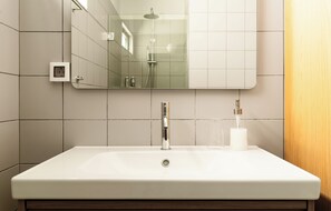 Ein Badezimmer mit einem weißen Waschbecken, einem Spiegel und einer Dusche.