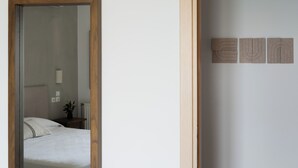 A bedroom with a bed, a nightstand with a plant, and a mirror. - Footsteps to the beach! (Agios Nikolaos)