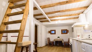 Una cocina con vigas de madera, una mesa de comedor, sillas y un ventanal.