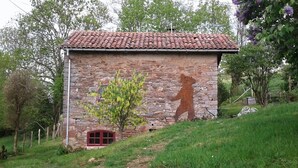 Um edifício de pedra com telhado de cerâmica, uma janela vermelha e um mural de urso.