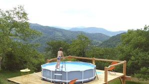 Piscina ao ar livre em deck de madeira com vista para colinas.