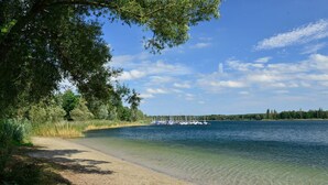 A beach with clear water, a row of boats, and a forested area. - House / Villa - BOLSENA (Bagnoregio)