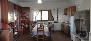 Ein Essbereich mit einem Tisch für vier Personen, Holzschränken, einem Kamin und einem Fenster mit Vorhängen.