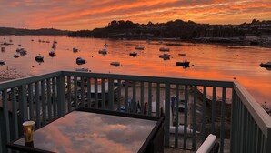 A sunset view from a balcony overlooking a harbor with boats, a table, and chairs. - 4 bed spacious modern townhouse with spectacular views over the River Tamar.  (Plymouth)