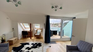 A spacious room with a large window, a bed, a chair, a table, and a view of the outside. - 4 bed spacious modern townhouse with spectacular views over the River Tamar.  (Plymouth)