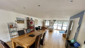 A spacious room with a wooden dining table, chairs, a sofa, and a view of the sea through large windows. - 4 bed spacious modern townhouse with spectacular views over the River Tamar.  (Plymouth)
