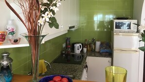 A kitchen with green tiles, a white refrigerator, a microwave, a sink, and various kitchen items.