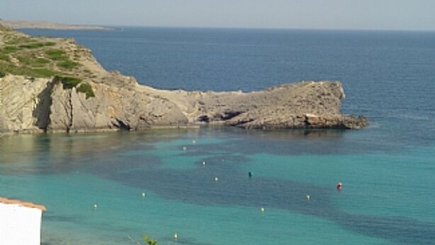 A coastal landscape with a rocky cliff and calm sea.