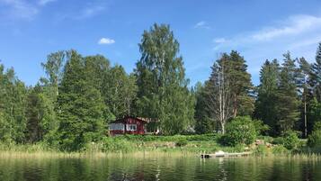 En stuga vid en sjö, omgiven av tät skog.