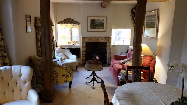A cozy living room with a fireplace, floral-patterned armchairs, and a dining table.