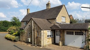 A stone house with a garage, a chimney, and a small garden.
