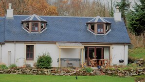 A traditional house with a stone wall, a covered porch, and two dormer windows. - Spacious Riverside Cottage Perfect For Families, groups,pets. ** NEW HOT TUB** (Glasgow)