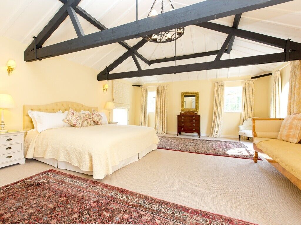 A spacious bedroom with a large bed, a sofa, and a wooden cabinet.