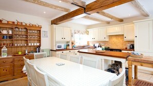 A spacious kitchen with wooden beams, white cabinetry, and a central island.