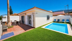 Ein Wohnhaus mit Swimmingpool, Terrasse und Gartenmöbeln, mit Blick auf die Berge.