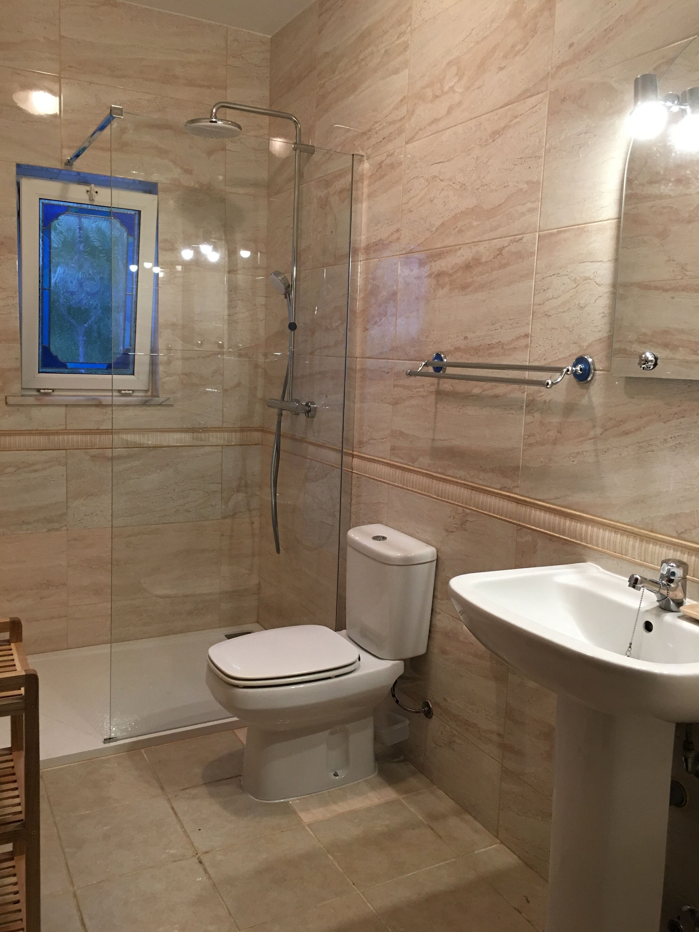 Une salle de bain avec une douche à parois de verre, des toilettes et un lavabo.