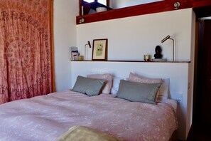 A bed with a patterned bedspread, pillows, a shelf with decorative items, and a framed picture on the wall. - Secluded Casa Simba: Relaxation Oasis with Private Pool and Sea View i (Pájara)