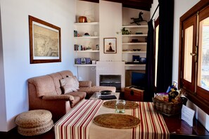 A living room with a sofa, a coffee table, a fireplace, and shelves with various items. - Secluded Casa Simba: Relaxation Oasis with Private Pool and Sea View i (Pájara)