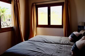 Un dormitorio con cama, cortinas, una ventana y una lámpara.