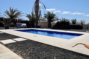 A swimming pool with a tiled deck, surrounded by palm trees and a bench. - Secluded Casa Simba: Relaxation Oasis with Private Pool and Sea View i (Pájara)