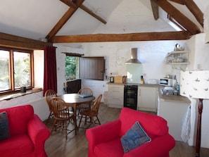 Open Plan living area with sofas dining area and wood burner.