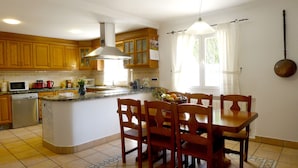 A kitchen with wooden cabinets, a built-in microwave, and a dining area with a table and chairs. - Ideal house to enjoy with your loved ones. (Santa Gertrudis de Fruitera)