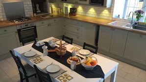 A modern kitchen with white cabinets, a wooden countertop, and a dining table set for four. - LARGE 4 BEDROOM FARMHOUSE  lots of charm, fully renovated 8+ (Bréhan)
