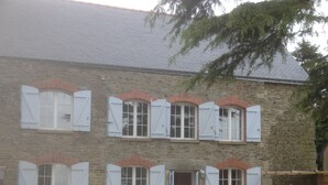 A stone building with multiple windows and a door, surrounded by gravel and a tree. - LARGE 4 BEDROOM FARMHOUSE  lots of charm, fully renovated 8+ (Bréhan)