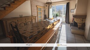 Un comedor espacioso con una larga mesa de madera, bancos y una escalera que lleva a un balcón.