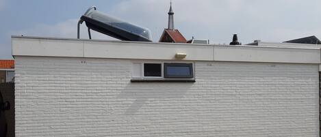 Un edificio con fachada de ladrillo blanco, una ventana pequeña y una chimenea.